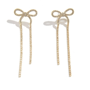 Detail of golden bow earrings featuring long tassels and shimmering white zircon pavé