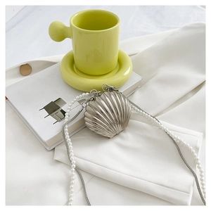 Detailed close-up of a silver shell-shaped mini bag with elegant pearl and metal chain strap