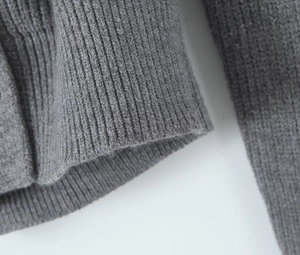 Detailed macro view of the grey knit sweater showing fine rib stitching and fabric texture