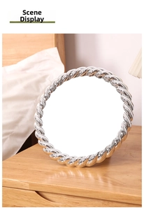 Detailed view of a vintage silver vanity mirror with a twisted rope metal frame on a desk
