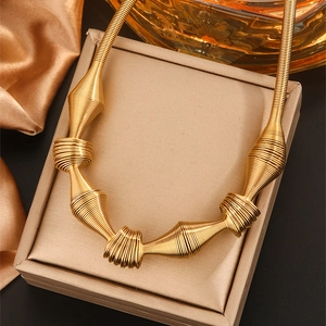 Golden titanium steel spring coil necklace on a beige jewelry display box with satin