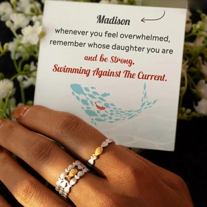 Detail of adjustable S925 sterling silver fish rings set worn on finger showing relief texture