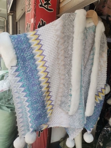 Detail of knitted ethnic shawl featuring faux rabbit fur collar and colorful zigzag patterns