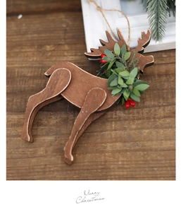 Detail of wooden reindeer ornament with green leaves and red berries on a rustic surface