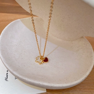 Détail du collier doré avec ours en zircon blanc et cœur rouge sur un bol en céramique