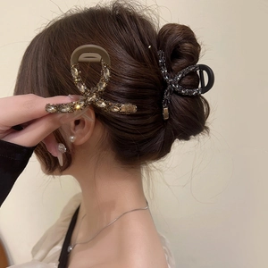 Elegant rhinestone shark hair claw clips in champagne gold and black on styled hair