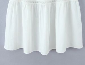 Macro view of white cotton skirt hem with delicate lace stitching and soft pleats