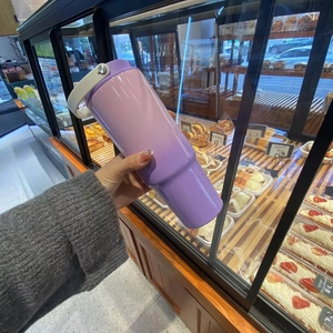Handheld 30oz lavender insulated travel mug with handle in a bakery setting