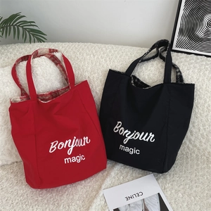 Detail of red and black tote bags with Bonjour magic print on soft white lamb wool background