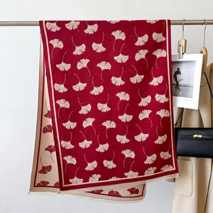 Detail of red and beige ginkgo leaf jacquard knit scarf with fine tassel fringe