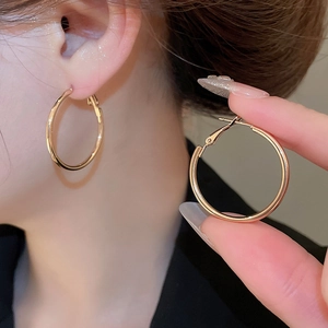 Close-up of classic large gold hoop earrings with a polished mirror finish on model