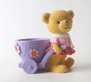 Dettaglio dell'orso giallo che spinge un carrello di fiori viola in resina per vasi