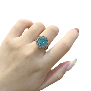 Elegant silver lotus ring with a large Paraiba blue gemstone on a model finger