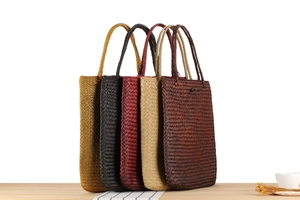 Detailed row of woven straw beach bags in yellow, black, burgundy, beige and brown