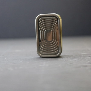 Macro shot of silver three-layer haptic coin EDC toy with concentric oval texture detail