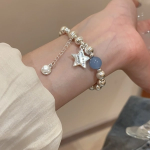 Close-up of beaded star bracelet with engraved shine like a star charm on wrist