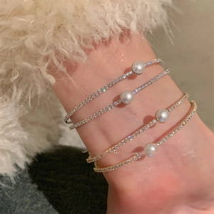 Close-up of elegant double-layered gold and silver bangles with pearls and crystals