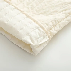 Detailed macro view of diamond quilted fabric with fine edge stitching in cream beige color