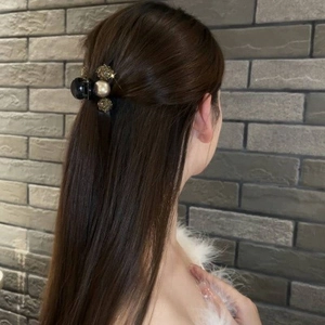 Detail of a chic black hair claw with pearls and gold accents on a half-up hairstyle