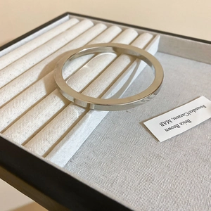 Detailed macro view of a silver polished flat rectangular bangle on a fabric tray