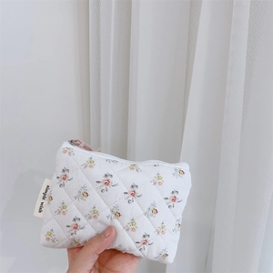Détail macro d'une mini pochette en coton matelassé à fleurs avec fermeture éclair