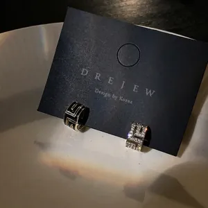 Boucles d'oreilles asymétriques en C avec émail noir et incrustation de zircons