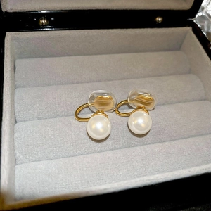 Detail shot of pearl ear clips in a gray velvet jewelry box with golden metal finish