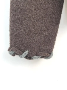Détail du poignet en maille marron foncé avec bordure grise et texture pelucheuse