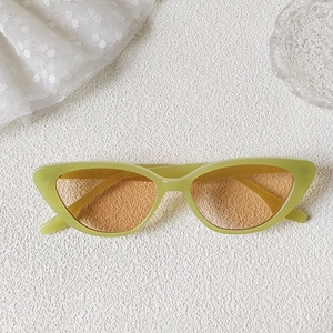 Detail of green cat-eye sunglasses with orange lenses on white lace and glass decor