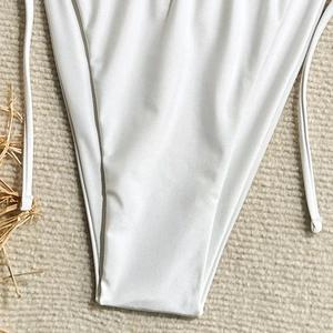 Macro view of white swimsuit bottoms showing silky texture and thin side tie details