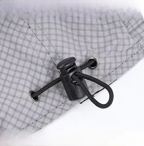 Macro detail of adjustable black elastic drawstring and buckle on grey plaid beret hat