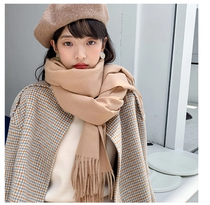 Close-up of soft camel cashmere-like knit scarf featuring elegant tassel edge detailing