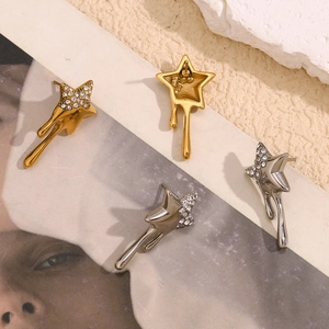 Detail of 18K gold and silver star earrings with lava texture and crystals on stone background