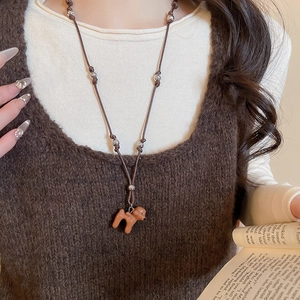 Détail du collier avec pendentif chiot marron et cordon tressé porté avec élégance