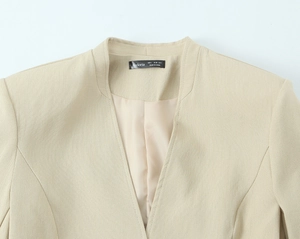 Detailed close-up of beige blazer neckline showing woven fabric texture and label brand