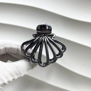 Detail of a sleek black fan-shaped metallic hair claw clip held with white gloves