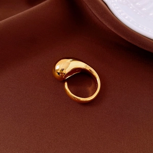 Macro shot of 925 silver stamp on gold fluid waterdrop ring over silk texture