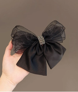 Detail of a black mesh and satin double bow hair clip with silver rhinestone buckle
