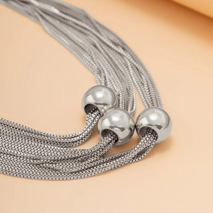Macro detail of multi-layer silver snake chains with polished metal ball pendants