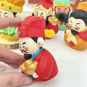 Close-up of hand-carved Caishen figurine in red robes holding a golden ingot