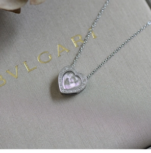 Macro shot of heart-shaped silver necklace featuring radial textures and pave diamond borders