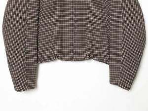 Detail shot of brown and white checkered tweed jacket hem and cuff with textured fabric