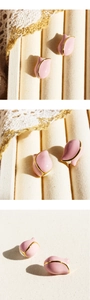 Macro detail of pink tulip earrings with gold edges on white lace fabric background