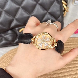 Detail of a women's watch with golden spinning rhinestone dial and black leather strap