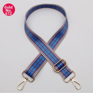 Macro detail of adjustable wide fabric shoulder strap with blue red grid and gold hooks