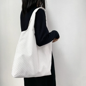 Detailed side view of large canvas tote bag with black polka dots on white background