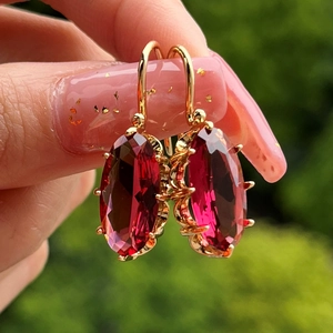 Detalle de pendientes vintage con piedras rojas ovaladas y engastes de garras doradas