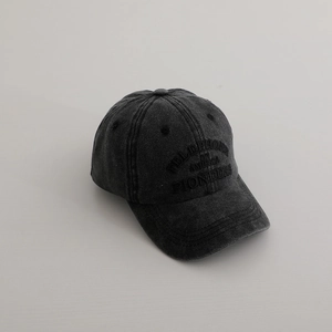Close-up of embroidered vintage lettering on a washed dark gray cotton baseball cap