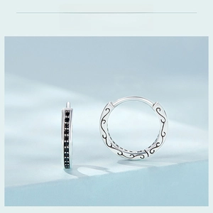 Macro shot of silver hoop earrings featuring black zircon pave and vintage scroll engravings