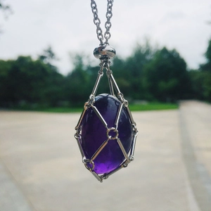 Close-up of a deep purple amethyst pendant in a silver mesh cage with a matching chain